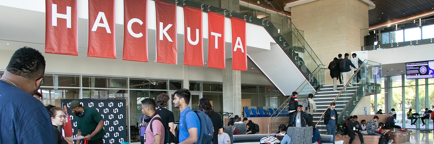 People sitting at a table, looking at a laptop that is on the table